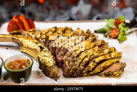 Tomahawk de bœuf de qualité supérieure enrobé d'or comestible Banque D'Images