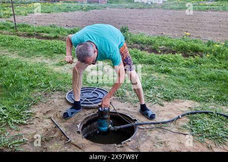 Pompe submersible d'eaux usées pour pomper les eaux usées contenant des matières fécales à partir d'une fosse septique dans les mains de l'homme qui entretient le puits. Banque D'Images