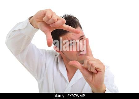 homme millénaire prétendant prendre une photo sur caméra imaginaire, regardant à travers elle clignant un œil sur fond blanc de studio Banque D'Images