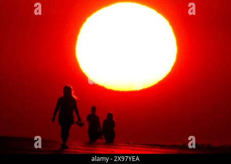 Île de Palms, États-Unis. 29 mai 2024. Les gens silhouettés par le lever du soleil, marchent le long de la plage tandis qu'une vague de chaleur balaye la région apportant des températures dans les années 90, 29 mai 2024 à Isle of Palms, Caroline du Sud. Crédit : Richard Ellis/Richard Ellis/Alamy Live News Banque D'Images