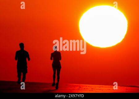 Île de Palms, États-Unis. 29 mai 2024. Les gens silhouettés par le lever du soleil, jogging le long de la plage alors qu'une vague de chaleur balaye la région, apportant des températures dans les années 90, 29 mai 2024 à Isle of Palms, Caroline du Sud. Crédit : Richard Ellis/Richard Ellis/Alamy Live News Banque D'Images