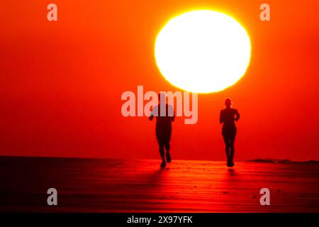 Île de Palms, États-Unis. 29 mai 2024. Les gens silhouettés par le lever du soleil, jogging le long de la plage alors qu'une vague de chaleur balaye la région, apportant des températures dans les années 90, 29 mai 2024 à Isle of Palms, Caroline du Sud. Crédit : Richard Ellis/Richard Ellis/Alamy Live News Banque D'Images