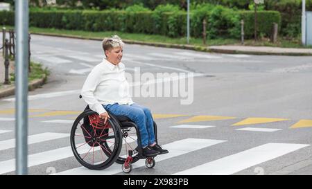 Femme handicapée sur un fauteuil roulant dans la rue de la ville. Banque D'Images