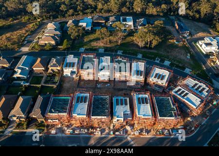 Vue aérienne en fin d'après-midi des maisons australiennes modernes en construction avec panneaux solaires et échafaudages dans la banlieue de Sydney. Banque D'Images