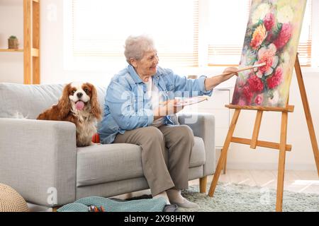 Femme senior avec la peinture de chien cavalier roi Charles spaniel mignon à la maison Banque D'Images