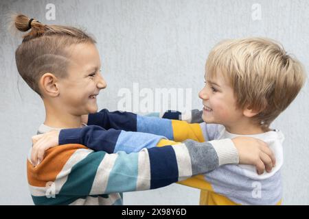 Deux frères ou amis de 7 ans, face à face, s'embrassant, s'amusant. la joie de la communication, le dorlotage, une joyeuse rencontre de classe Banque D'Images