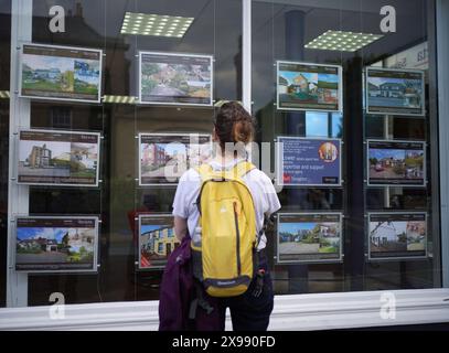 Photo du dossier datée du 20/07/23 d'une femme regardant des annonces dans une fenêtre d'agents immobiliers. L'offre britannique de maisons à vendre est à son point le plus élevé en huit ans, selon la recherche, dans une tendance qui, selon les experts, limitera les hausses de prix des maisons pour le reste de l'année 2024. Zoopla, le site Web de l'immobilier, a déclaré que l'agent immobilier moyen a 31 maisons à vendre, en hausse de 20% par rapport au même point l'an dernier et le nombre le plus élevé depuis 2016. Date d'émission : jeudi 30 mai 2024. Banque D'Images