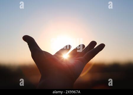 Les mains tendues vers le soleil levant au lever du soleil du nouvel an, une lumière brillante brillante entre les doigts, l'espoir futur et le concept d'espoir Banque D'Images