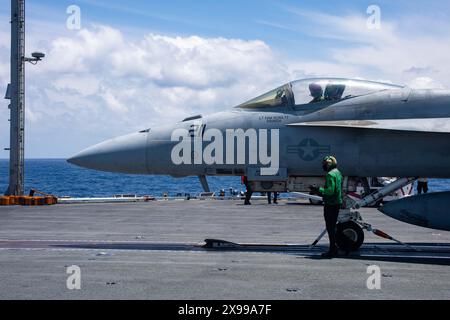 Mer des Philippines, États-Unis. 29 mai 2024. Un marin de lancement et de récupération de l'US Navy vérifie le câble de catapulte d'un chasseur F/A-18E Super Hornet attaché au Royal Maces of Strike Fighter Squadron 27, avant de décoller sur le pont d'envol du porte-avions USS Ronald Reagan de classe Nimitz en cours, le 29 mai 2024, dans la mer des Philippines. Crédit : MC2 Evan Mueller/US Navy photo/Alamy Live News Banque D'Images