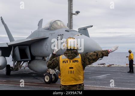 Mer des Philippines, États-Unis. 24 mai 2024. Un marin de la U.S. Navy Aircraft Handling signale à un chasseur F/A-18E Super Hornet attaché au Royal Maces of Strike Fighter Squadron 27, de s'aligner pour décoller sur le pont d'envol du porte-avions USS Ronald Reagan de classe Nimitz en cours de route, le 24 mai 2024, sur la mer des Philippines. Crédit : MC2 Caleb Dyal/US Navy photo/Alamy Live News Banque D'Images