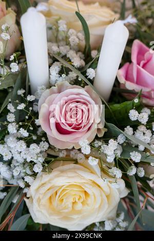 Pièce maîtresse d'arrangement floral avec des bougies blanches dans le bouquet de roses de couleur pastel, le souffle et la verdure de bébé, belle décoration Banque D'Images