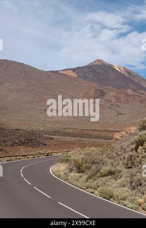 Route sinueuse traversant le parc national du Teide avec vue sur le stratovolcan important et le plus haut sommet du pays, Tenerife, Espagne Banque D'Images