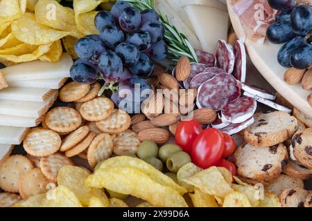 Arrangement de charcuterie avec fromage espagnol soigneusement tranché, jambon serrano, craquelins ronds, chips croquantes, raisins noirs, amandes entières et plus encore Banque D'Images