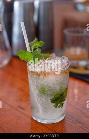 Cocktail mojito rafraîchissant sur un comptoir de bar prêt à être servi, délicieuse boisson alcoolisée préparée dans un verre clair avec de la glace pilée, menthe fraîche Banque D'Images