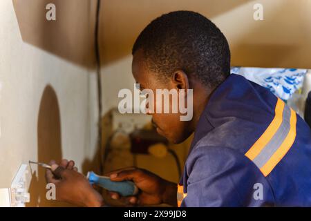 technicien africain avec un tournevis installant un terminal de fibre optique dans une salle pour internet amélioré Banque D'Images