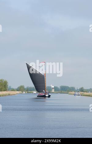 Les gens naviguent sur un bateau à voile traditionnel sur la rivière Bure, montrant St Benet's drainage Mill Banque D'Images