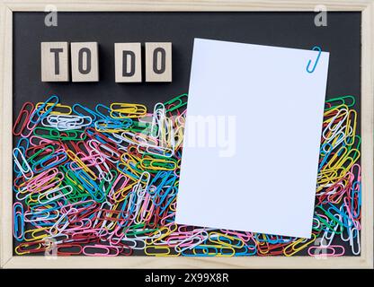 Fond noir avec trombones colorés, espace copie blanc et cubes en bois avec le texte : Todo Banque D'Images