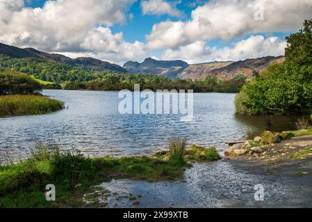 Scène tranquille au bord de l'eau Elter dans le parc national de Lake District towrds Birk Rigg Park Coppice. Les brochettes Langdale en arrière-plan. Banque D'Images