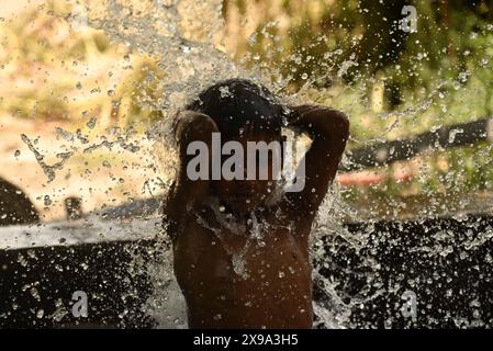 Delhi, New Delhi, Inde. 30 mai 2024. Un garçon prend une douche sous l'eau qui coule d'un pipeline par un chaud après-midi d'été au milieu de la canicule en cours à New Delhi, Inde le 30 mai 2024 (crédit image : © Deep Nair/ZUMA Press Wire) USAGE ÉDITORIAL SEULEMENT! Non destiné à UN USAGE commercial ! Banque D'Images