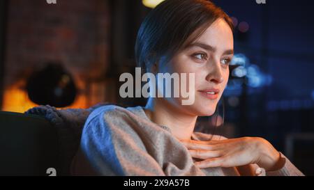 Portrait de belle femme passer du temps à la maison, se reposer sur un canapé, regarder l'émission de télévision d'horreur dans un élégant appartement loft. Jeune femme profiter de regarder Scary Movie seul sur le service de streaming. Banque D'Images