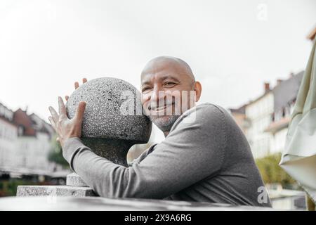 Homme âgé souriant profitant de la journée dehors dans un environnement urbain Banque D'Images