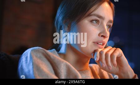 Portrait de belle femme passer du temps à la maison, se reposer sur un canapé, regarder l'émission de télévision d'horreur dans un élégant appartement loft. Jeune femme profiter de regarder Scary Movie seul sur le service de streaming. Banque D'Images