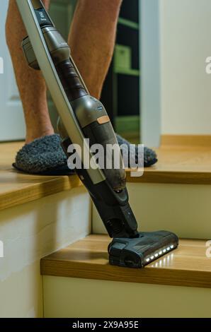 Image découpée d'un homme passant l'aspirateur à la maison et faisant des tâches ménagères. Photo de haute qualité Banque D'Images