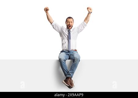 Homme professionnel assis sur un panneau blanc et levant les bras isolés sur fond blanc Banque D'Images