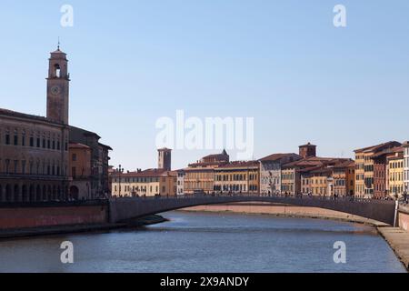 Pise, Italie - mars 31 2019 : le Palazzo Pretorio et sa tour de l'horloge en face du Ponte Di Mezzo au-dessus du fleuve Arno. Banque D'Images