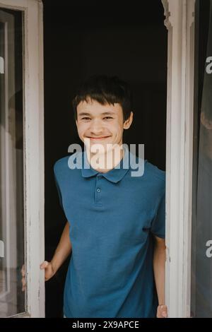 Portrait d'adolescent souriant debout à la porte de la maison Banque D'Images