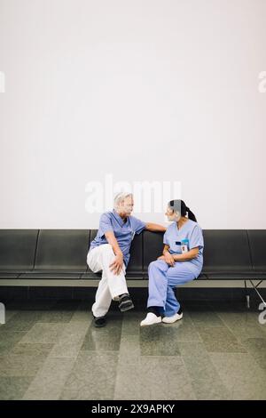 Médecins hommes et femmes discutant en étant assis sur le banc à l'hôpital Banque D'Images
