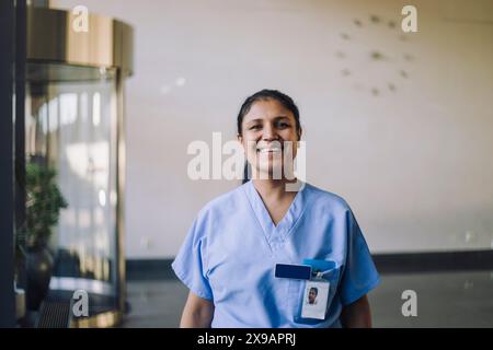 Portrait d'une femme médecin souriante dans des gommages bleus debout à l'hôpital Banque D'Images