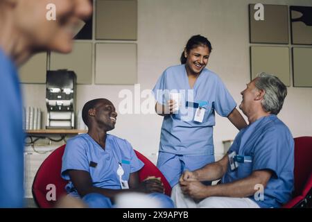 Heureux médecins multiraciaux parlant à la cafétéria de l'hôpital pendant la pause café Banque D'Images