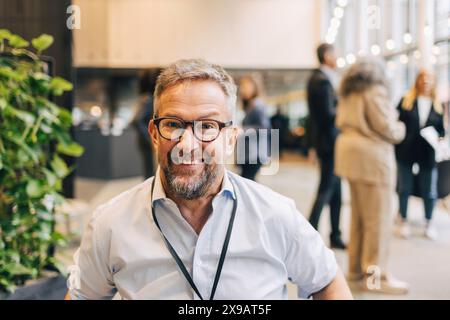 Portrait d'entrepreneur masculin souriant portant des lunettes pendant le séminaire au centre des congrès Banque D'Images