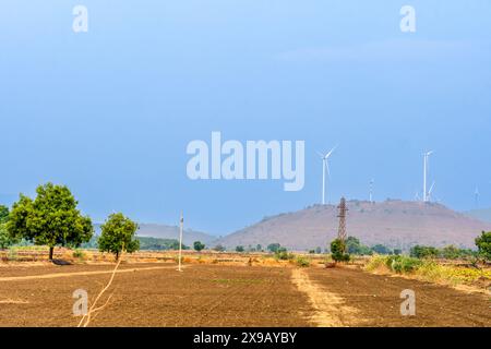 Dans ce paysage captivant, les éoliennes se dressent face à un ciel bleu immaculé. La rangée d’éoliennes à l’horizon symbolise le progrès, Sustainab Banque D'Images