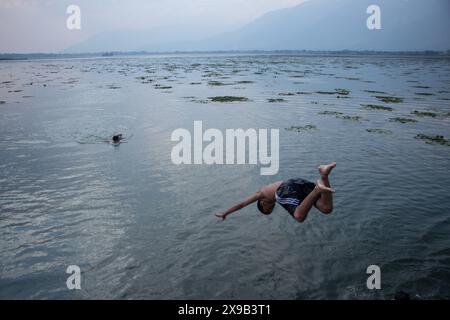 Srinagar, Jammu-et-Cachemire, Inde. 30 mai 2024. Un garçon saute dans le lac Dal pour chercher un soulagement de la chaleur lors d'une chaude journée d'été à Srinagar. (Crédit image : © Adil Abass/ZUMA Press Wire) USAGE ÉDITORIAL SEULEMENT! Non destiné à UN USAGE commercial ! Banque D'Images