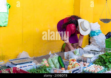 Paysanne latine vend des légumes sur une place du marché, elle porte des vêtements traditionnels et un chapeau, les légumes sont frais et l'image a de la place Banque D'Images