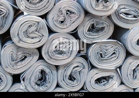 Rouleaux de plastique gris empilés de manière désordonnée, créant un bruit de papier rouleau Banque D'Images