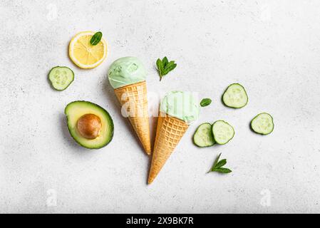 Cuillères à crème glacée avocat vert noix de coco dans des cônes gaufrés sur fond blanc, vue de dessus. Crème glacée végétalienne tendance aux légumes verts : concombre, brocoli Banque D'Images