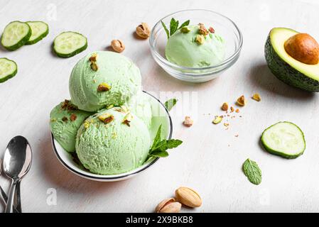 Cuillères à glace avocat vert noix de coco avec pistaches dans un bol. Crème glacée végétalienne maison à la mode avec légumes verts. Banque D'Images