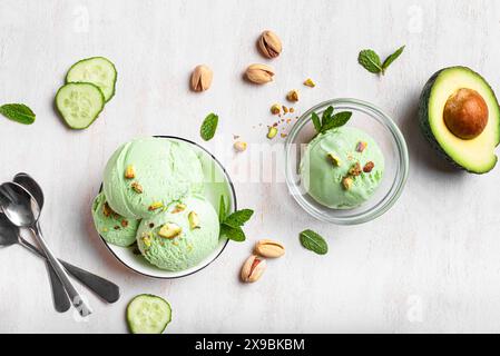 Cuillères à glace avocat vert noix de coco avec pistaches dans un bol. Crème glacée végétalienne maison à la mode avec légumes verts. Banque D'Images