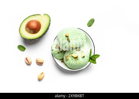 Cuillères à crème glacée à la pistache et à la noix de coco d'avocat vert dans un bol isolé sur fond blanc. Crème glacée végétalienne maison tendance avec feuilles de menthe verte et avoc Banque D'Images