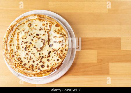 Photographie de nourriture de table d'une assiette blanche de fines crêpes se tient sur le côté sur une table en bois de hêtre Banque D'Images