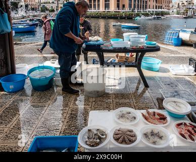Pêcheur préparant des fruits de mer frais pour la vente sur un marché Harborside à Bari, Italie Banque D'Images
