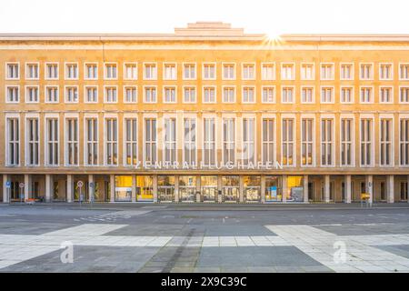 La lumière du soleil s'illumine au-dessus du terminal historique de l'aéroport Tempelhof à Berlin, projetant une lueur chaude sur sa façade. Banque D'Images