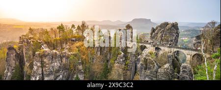 La lumière dorée baigne le pont Bastei et les formations rocheuses de grès environnantes à l'aube en Suisse saxonne, en Allemagne. Banque D'Images