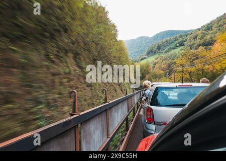 Les jeunes garçons se penchent par la fenêtre d'une voiture alors qu'elle se déplace à l'arrière d'un wagon de train à moteur alors qu'elle traverse des tunnels et des gorges en Slovénie Banque D'Images