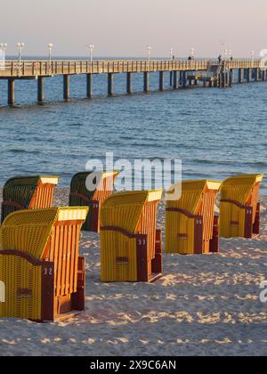 Un quai s'étend dans la mer, entouré de chaises de plage sur la plage de sable dans la lumière chaude du soir, atmosphère d'automne sur la plage de Binz avec Banque D'Images