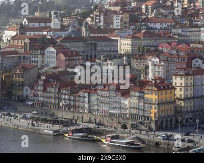 Paysage urbain par une rivière, bordée de maisons avec des toits rouges et des bâtiments historiques, printemps dans le vieux centre-ville de Porto sur le Douro avec Banque D'Images