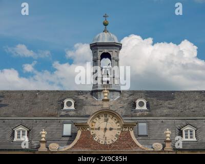 Une tour de l'horloge sur un château historique sous un ciel bleu avec des nuages blancs, vieux château en briques rouges avec des tours et un grand parc avec des arbres, des plantes et Banque D'Images